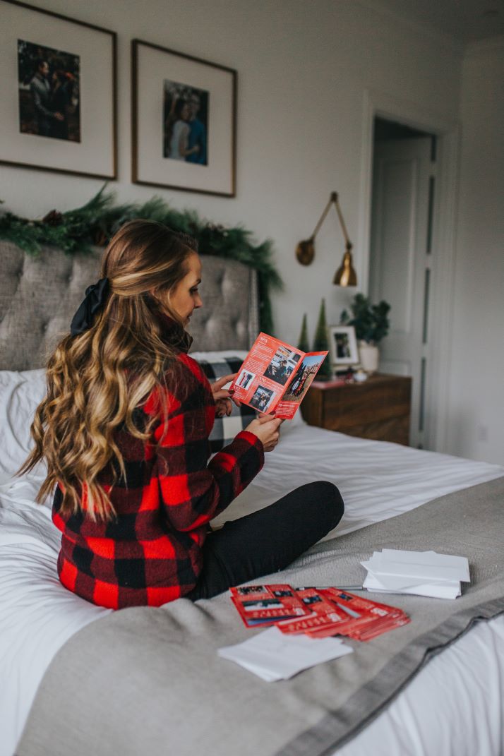 girl in buffalo check jacket on the bed with mixbook cards