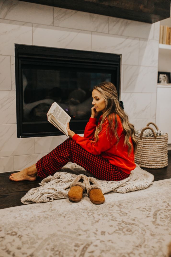 red plaid pajama pants red sweatshirt by the fireplace