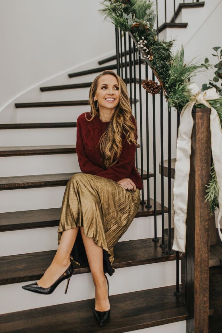 merrick on stairs with gold pleated skirt and burgundy cable knit sweater